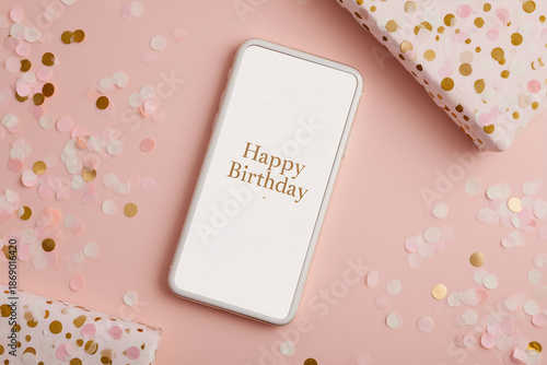 Birthday greeting displayed on a mobile phone surrounded by colorful confetti and gift wrap for a festive celebration