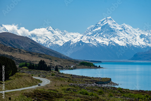 Winding road next to a glacial lake leading to a Mountain Range