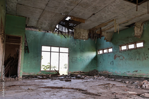 Dilapidated building interior with natural light shining through the window and damaged roof, creating a sense of abandonment and decay