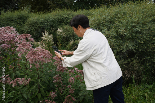 Woman enjoying nature while taking photos of flowers 