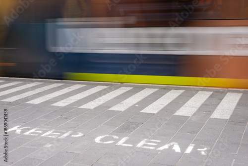 A Keep Clear notice in the forground with a train in motion in the background, train blurred