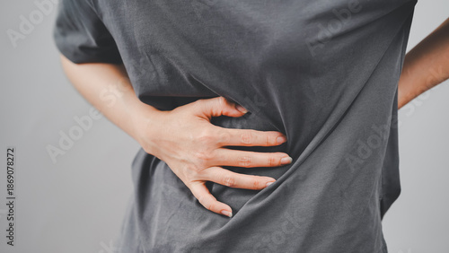 Close-up of a person holding their side in pain, indicating discomfort in the abdominal or kidney area with visible body tension.
