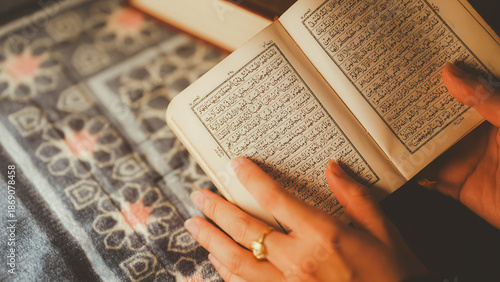 A close-up of a Muslim woman reading the Quran, holding the holy book with Arabic text on a patterned prayer mat, symbolizing Islamic faith, worship, and spirituality.