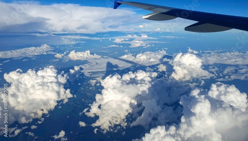 Aerial view of fluffy white clouds from an airplane window with wing visible.