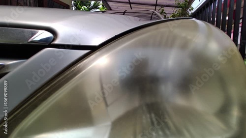 Close-up of a faded and cloudy car headlight showing signs of aging, oxidation, and wear. Represents vehicle maintenance, automotive repair, safety issues, and used car condition.