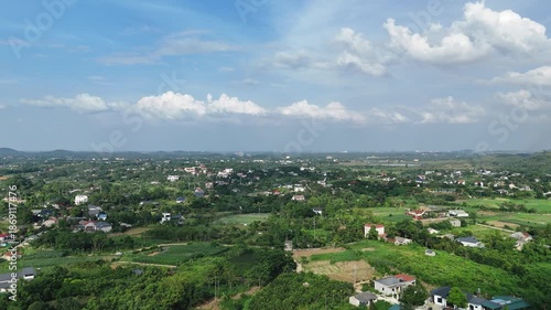 Panoramic drone shot of emerald rice fields at the foot of Ba Vi mountains.