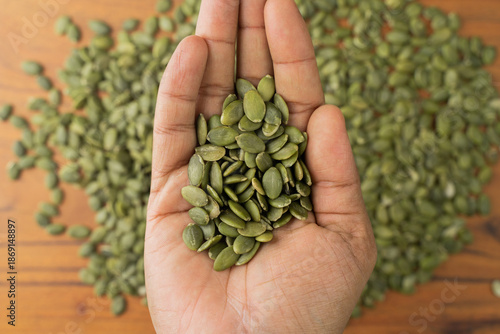 Green Pumpkin seeds are placed on a hand.