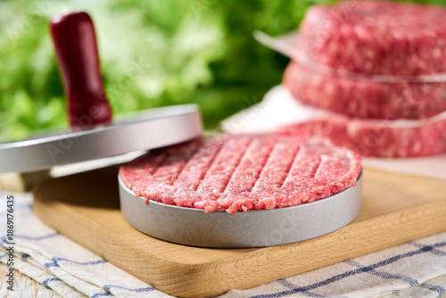 Fotografía Fresh raw ground beef patties with salt and pepper made in a burger press on a cutting board