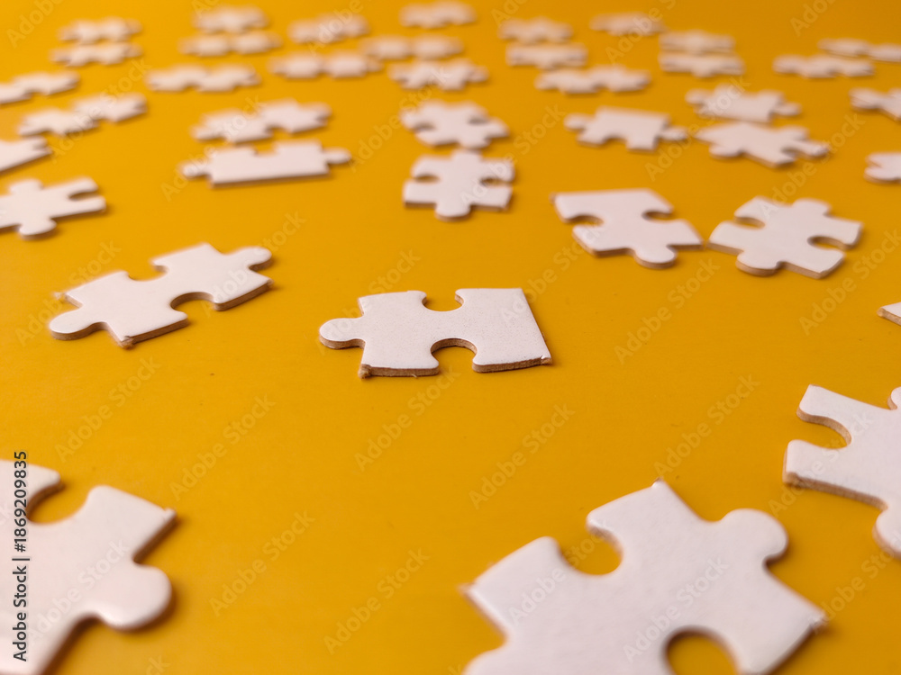 Fototapeta premium Pieces of a jigsaw puzzle scattered across a yellow background
