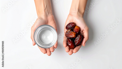 Hands holding dates and a bowl of water in a serene white environment