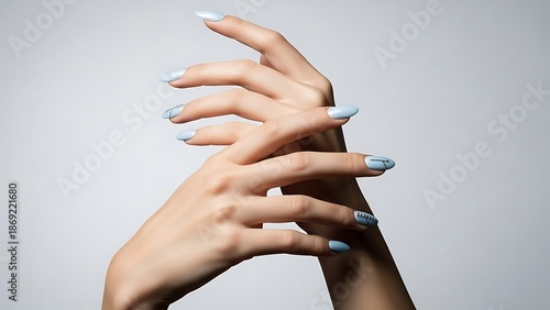 Elegantly poised female hands adorned with delicate light blue manicured nails, captured in a serene gesture conveying refined beauty and graceful sophistication