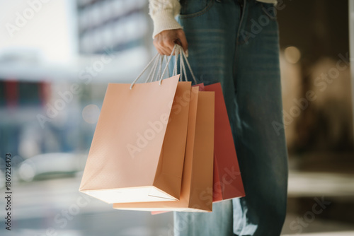 Bilde på lerret Close-up of a young woman holding multiple shopping bags while walking outdoors, symbolizing retail shopping, consumer lifestyle, and modern urban purchasing behavior