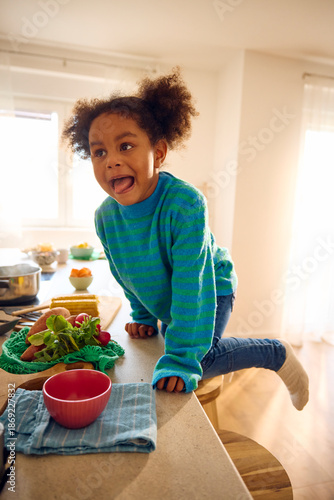 Little girl climbs the kitchen