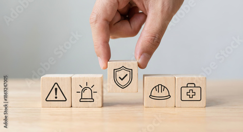 Hand putting a wooden cube with protection shield icon among safety and health symbols