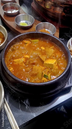 Boiling Korean Traditional Kimchi Stew with Tofu in an Earthen Pot (Ttukbaegi)