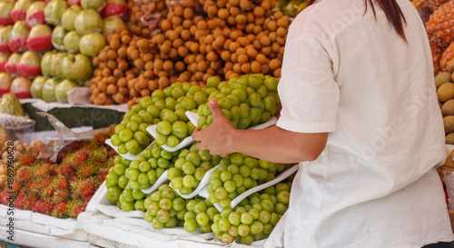 Billede på lærred A woman is standing in front of a fruit stand