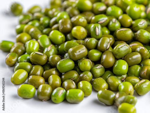 A close-up, high-angle view of a pile of raw, dried mung beans (Vigna radiata), also known as green gram, scattered on a plain white background. 
