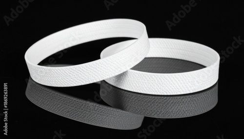 Two white hook-and-loop fastener strips on reflective black surface, one flat and one slightly curved.