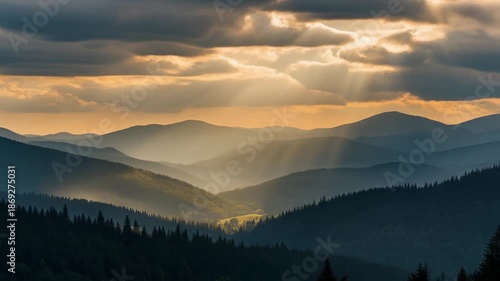 Sunset over mountainous landscape with rays of light piercing through clouds and trees