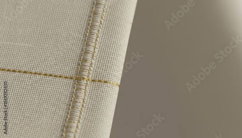 Beige fabric with stitched seam closeup, textile detail background