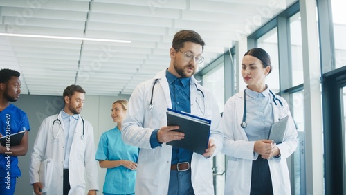 Fotografi Medical staff walking through bright clinic hallway talking with each other