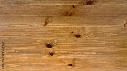 Knotted wooden tabletop with warm grain and visible knots, closeup of pine plank surface showing natural finish and subtle imperfections, ideal for food photography, furniture styling, workshop