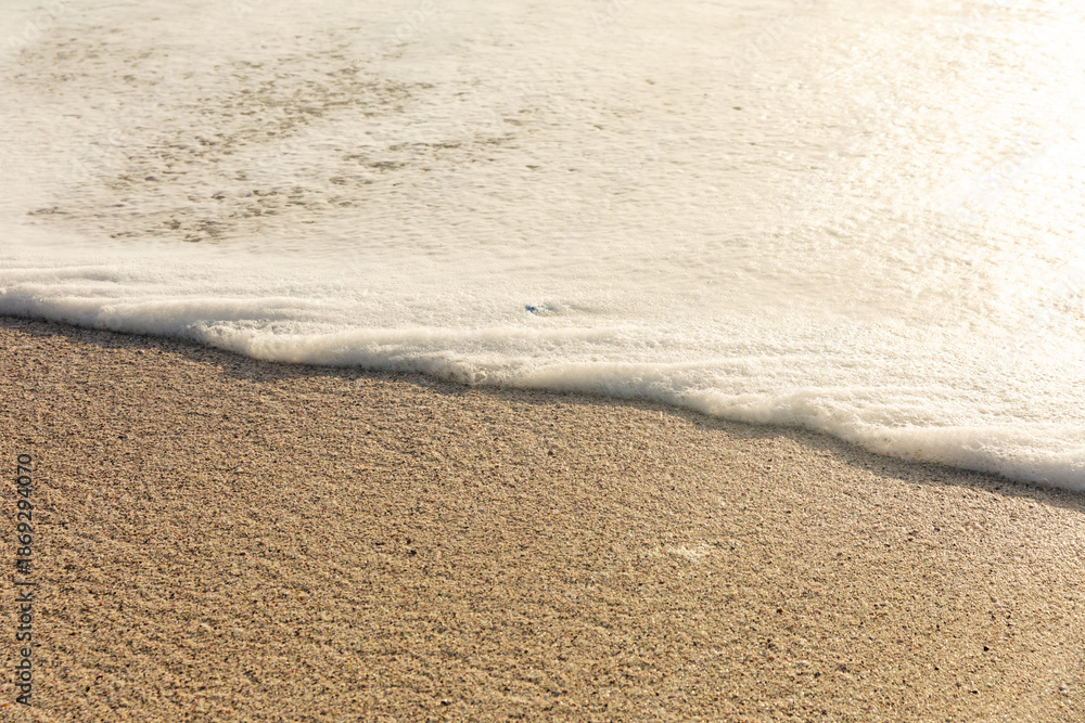 Fototapeta premium High angle view of white sea wave foam on shore at sunny beach