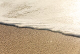 High angle view of white sea wave foam on shore at sunny beach