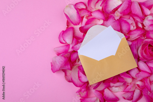 Overhead view of letter and envelope on flower petals isolated on pink background, copy space