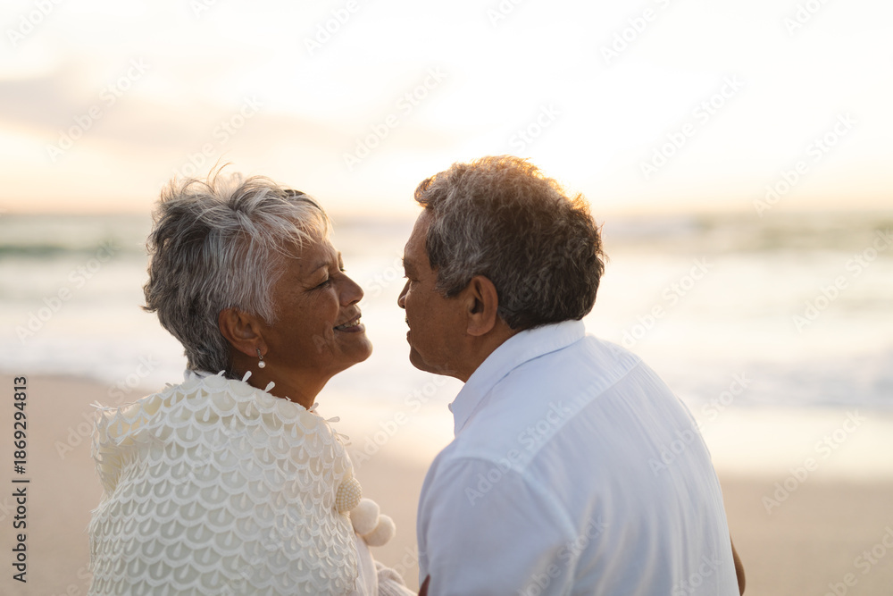 Fototapeta premium Side view of happy multiracial senior couple looking at each other romantically during sunset