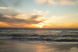 Scenic view of waves on shore at beach against sky during sunset