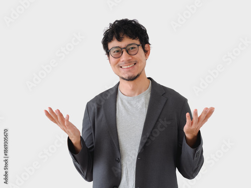Man in a suit and glasses is smiling and pointing to the sky