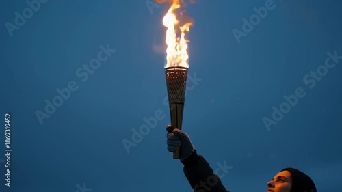 Ceremonial Torch in Athlete Glove with Swirling Snow Warm Firelight Lighting a Cold Winter Night