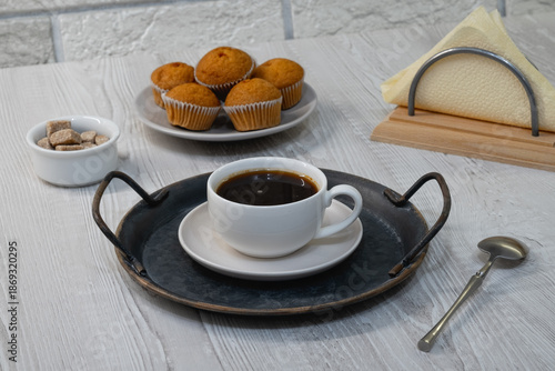 Fresh coffee served with muffins and sugar on a simple table setup in a cozy indoor space