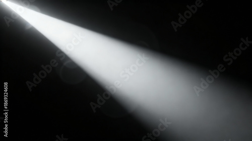 A dramatic, bright white spotlight beam cuts through the darkness, illuminating a path