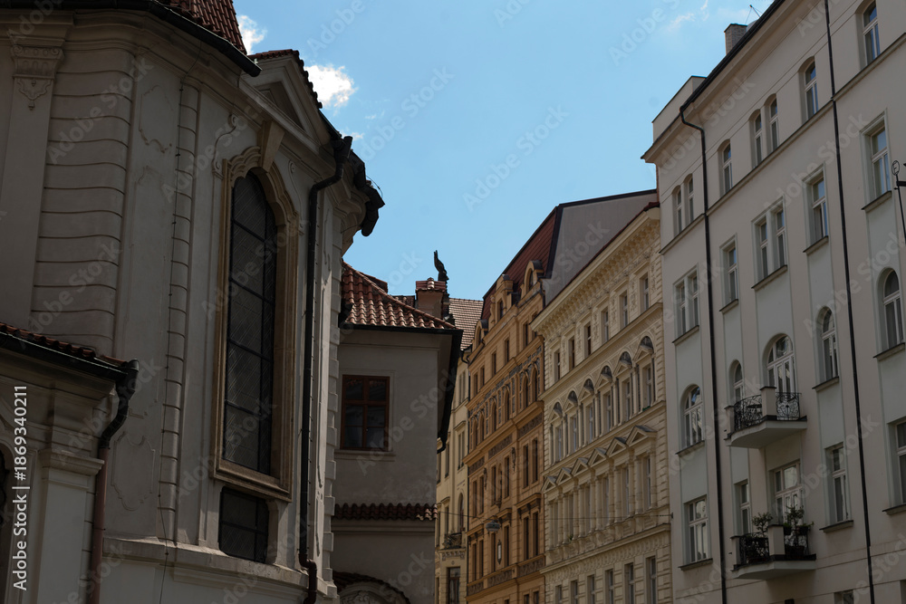 Fototapeta premium Ancient architecture visible through window, Historic alley with sunlit rooftops viewed from church, Old town scene featuring weathered roofs and sunlightdrenched streets from cathedral window