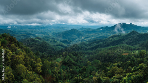 A vast mountain range covered in lush green forest under cloudy skies