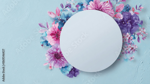 Soft pastel floral arrangement with a blank circular copy space on a textured blue background. Delicate watercolor flowers in shades of pink, purple, and blue.