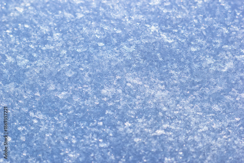 The closeup view of snowflakes and icy surface. The cold winter weather background with frosty crystals background.