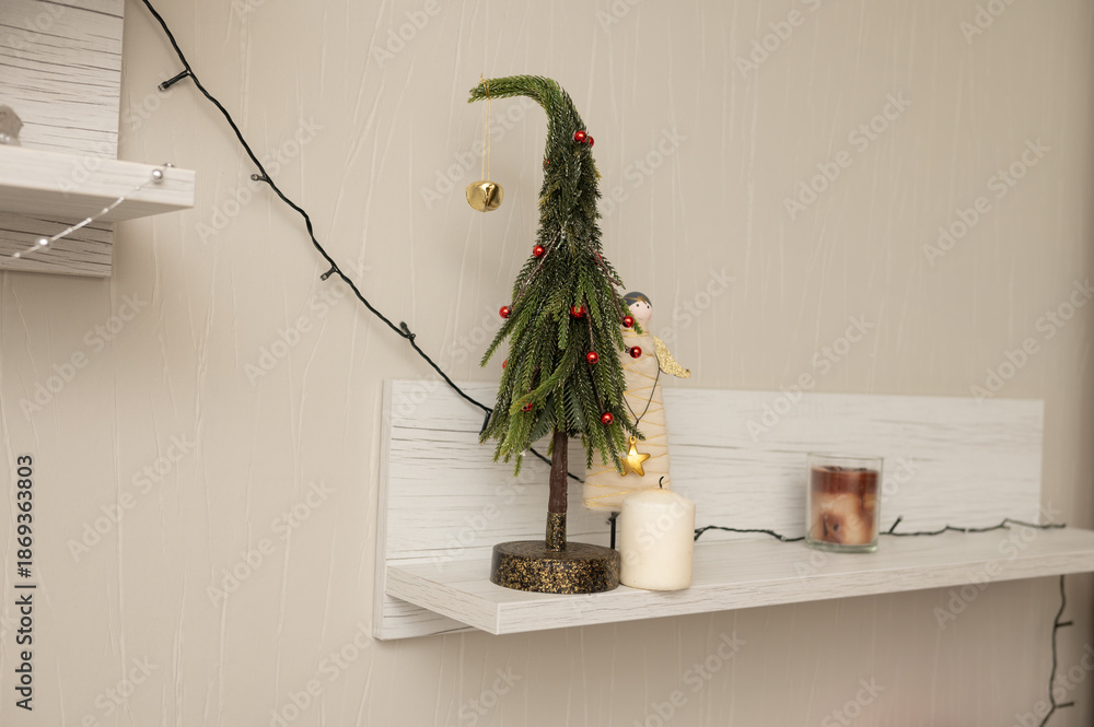 Fototapeta premium Decorative shelf with miniature christmas tree and candles in cozy interior