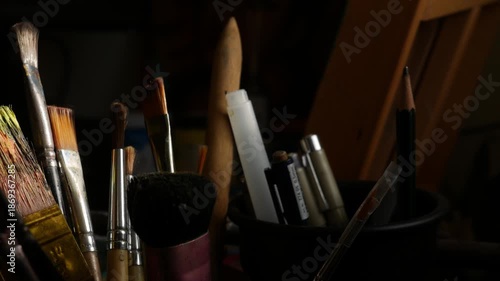 Collection of Used Artist Paintbrushes in Container with Paint Palette 