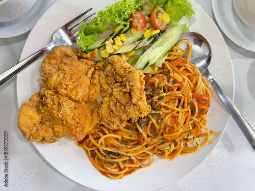 Crispy fried chicken served with spaghetti pasta and vegetables, hearty comfort food meal