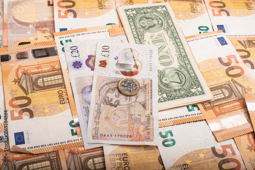 Close-up of international banknotes and coins: Pound, Euro, and Dollar.