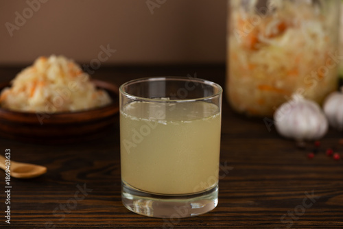 Fresh homemade sauerkraut juice or brine with sauerkraut salad in a plate and jar on a brown wooden table. Probiotic food.