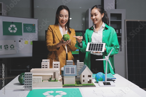 
 Two business people team planning and discussing of sustainable and renewable clean energy product with solar cell and wind turbine generator, CO2 emissions climate change global warming project