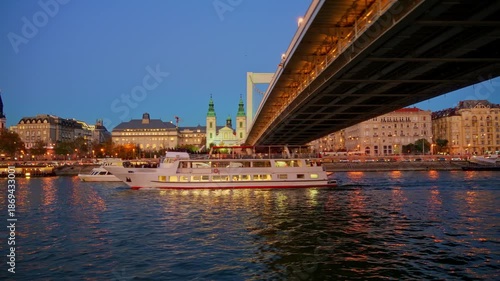 Panoramic view of Budapest city and Danube River at sunset, Elizabeth (Erzsebet) bridge, tour boats, urban architecture with beautiful illumination, street lights and road traffic
