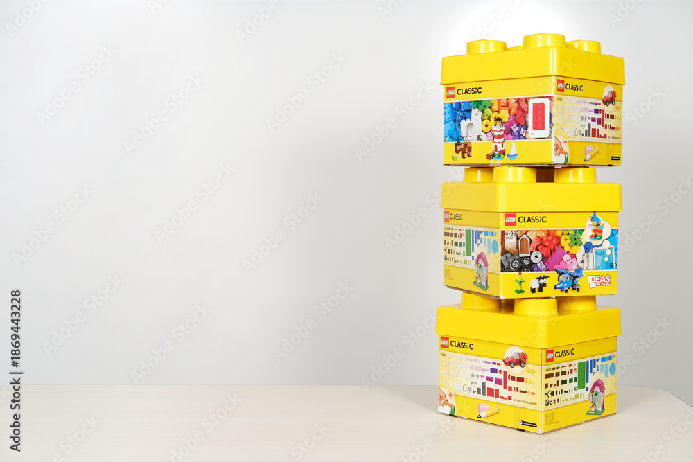 Obraz premium Minsk, Belarus - September 10, 2025: Lego constructor boxes stacked on a table with a white background, showcasing vibrant colors and playful designs, perfect for creative building concepts