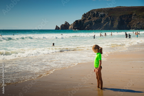Child girl with green t-shirt standing in Pen Hat beach on the atlantic coast in Camaret-sur-Mer. Finistere, Brittany, France. Profile portrait.