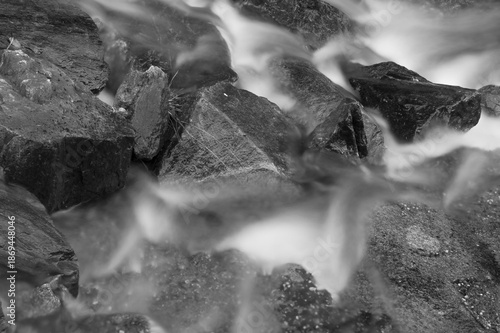 Cold water flowing over rocks in a waterfall before freezing.