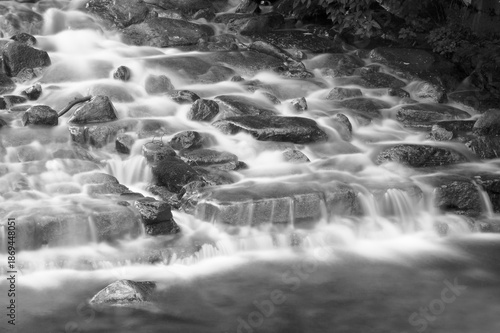 Cold water flowing over rocks in a waterfall before freezing.